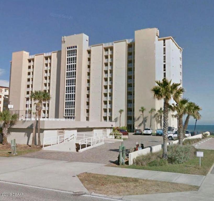a large building with palm trees in front of it at DIRECT OCEANFRONT NO-DRIVE BEACH CONDO in Daytona Beach