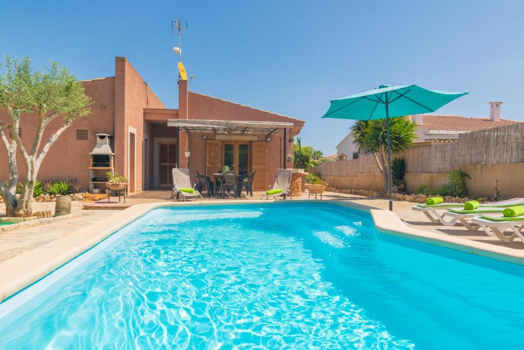 a swimming pool with an umbrella in front of a house at Can Cantari in Sa Coma