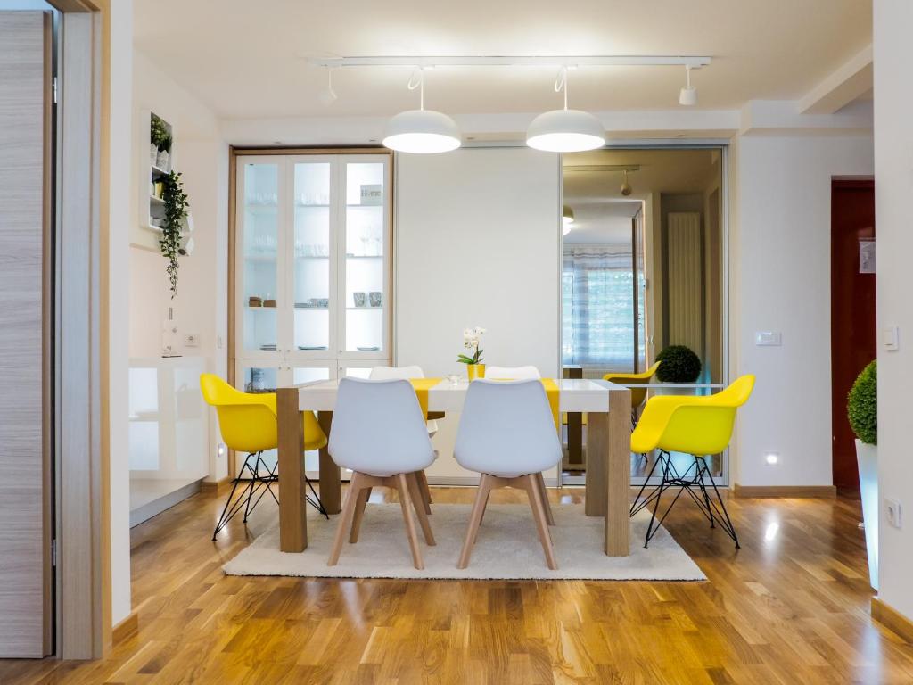 a dining room with a table and yellow chairs at Apartman Delux Adda in Zagreb