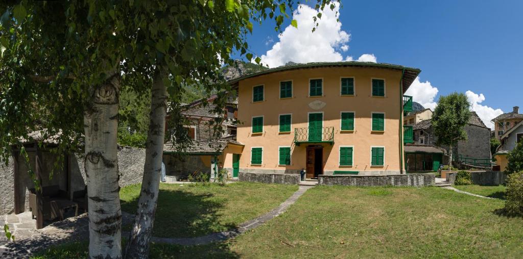 a building with green and yellow doors and a tree at Ca’d’ambra in Groscavallo