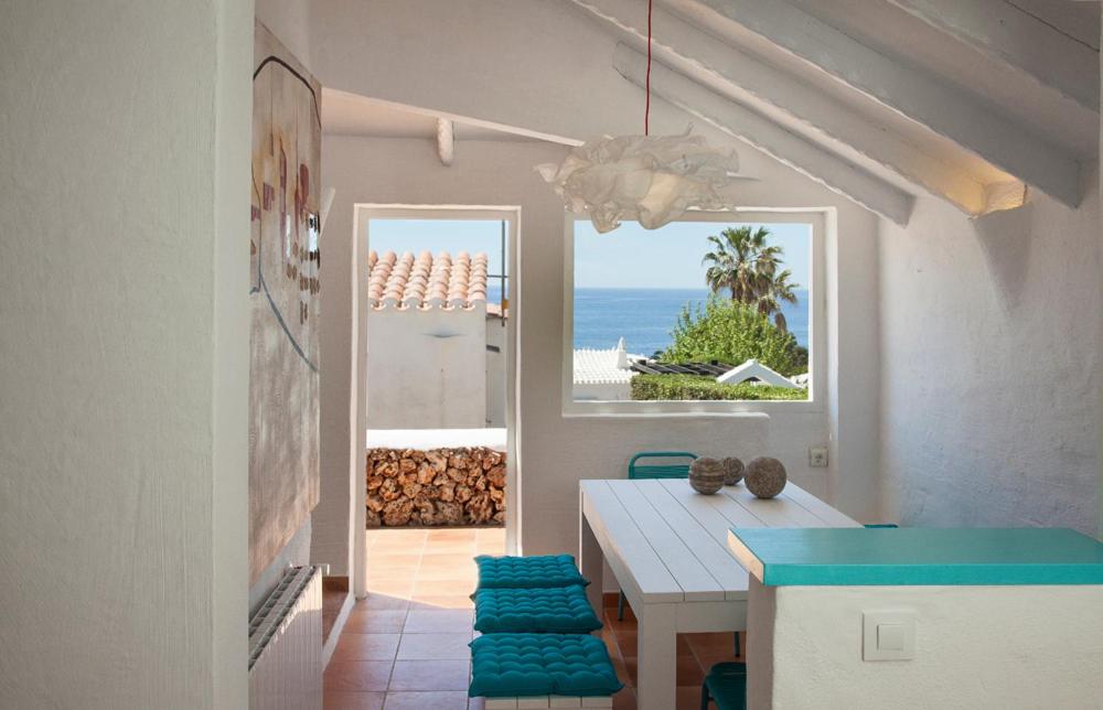 a dining room with a table and a view of the ocean at San Colomban in Sant Lluis