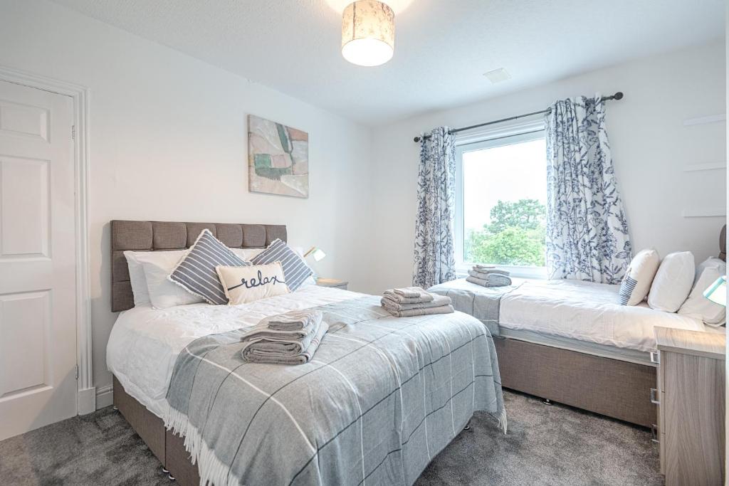 a bedroom with two beds and a window at Spacious house in Swansea TV in every bedroom in Swansea