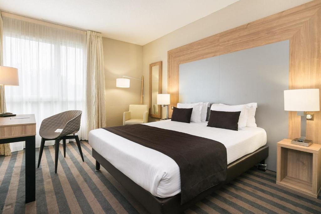 イルキルシュ・グラフェンスタデンにある7Hotel&Spaの大きなベッドとデスクが備わるホテルルームです。