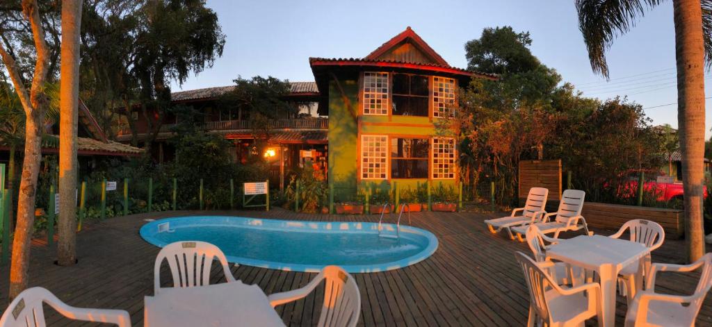 um resort com piscina e cadeiras e um edifício em Pousada Canoa Azul na Praia da Ferrugem em Garopaba