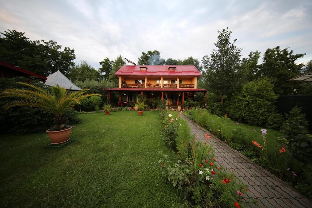 een huis met een rood dak in een tuin bij Pensiunea Criveanu in Horezu