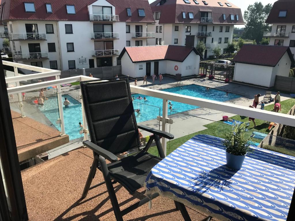 a chair sitting on a balcony next to a swimming pool at Middelkerke green garden in Middelkerke