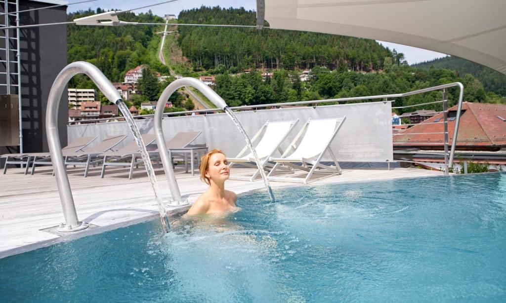 a woman in a swimming pool on a roof at Mokni's Palais Hotel & SPA in Bad Wildbad