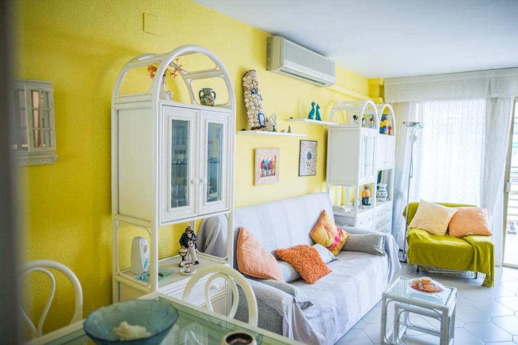 a living room with a couch and a yellow wall at Acogedor apartamento en primera linea de playa in Salou