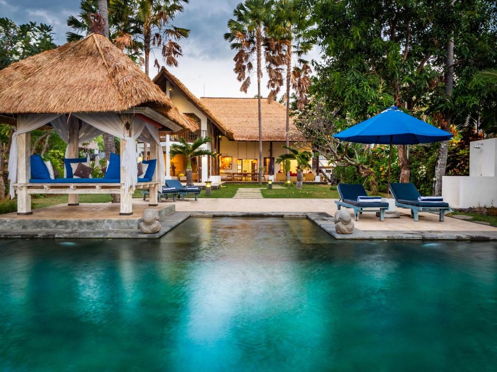 uma villa com uma piscina com cadeiras e um guarda-sol em Villa Cantik em Lovina
