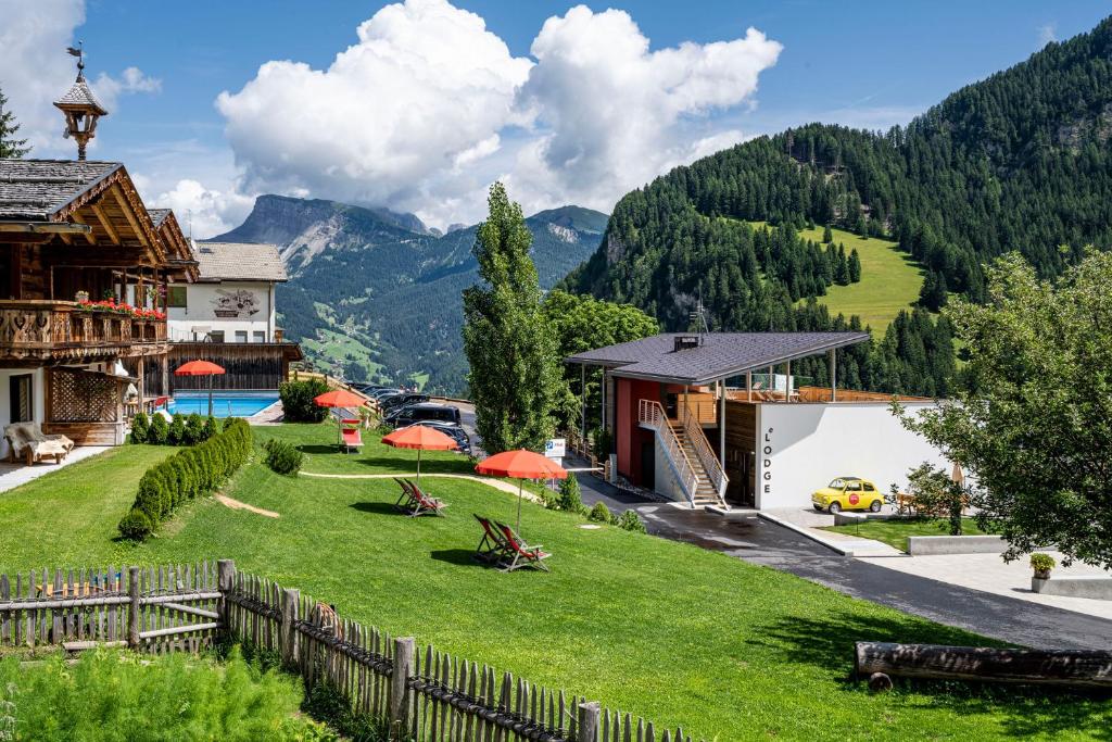 uma casa nas montanhas com um jardim verde em Hotel Platz em Ortisei