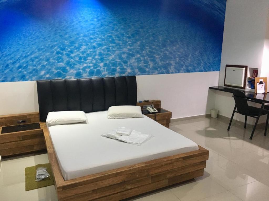 a large bed in a room with a large painting on the wall at Tennessee Motel ltda in Bragança Paulista