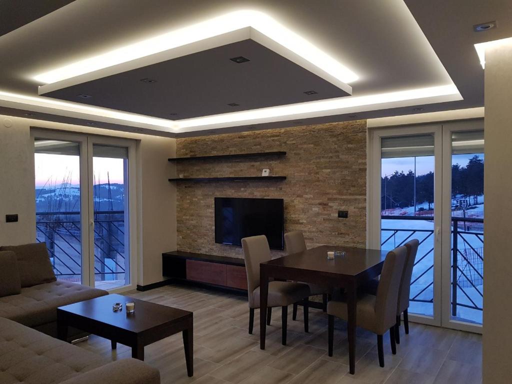 a living room with a dining table and a fireplace at Divcibare Delux Apartman in Divčibare