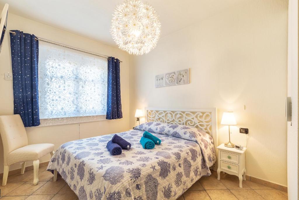 Un dormitorio con una cama con almohadas azules y una lámpara de araña. en Casa Vacanze Pedras, en Santa Maria Navarrese