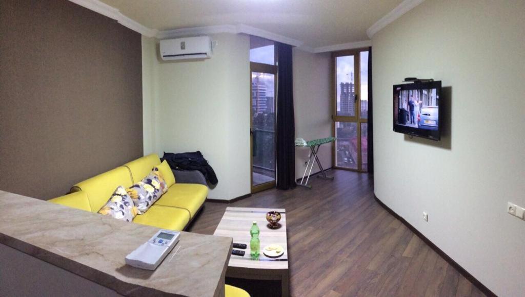 a living room with a yellow couch and a tv at Orbi Plaza Black Sea in Batumi