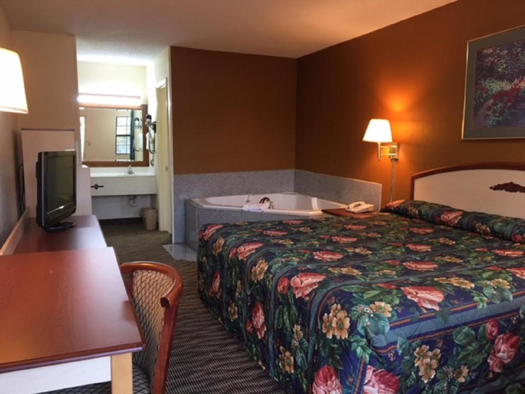 a hotel room with a bed and a bath tub at Suite Stay - Talladega in Talladega