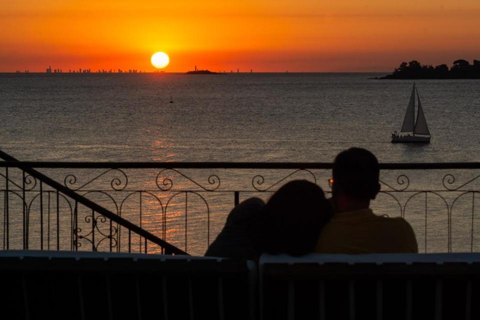 una pareja sentada en un banco viendo la puesta de sol en Casa Francis - Apartamentos, en Colonia del Sacramento