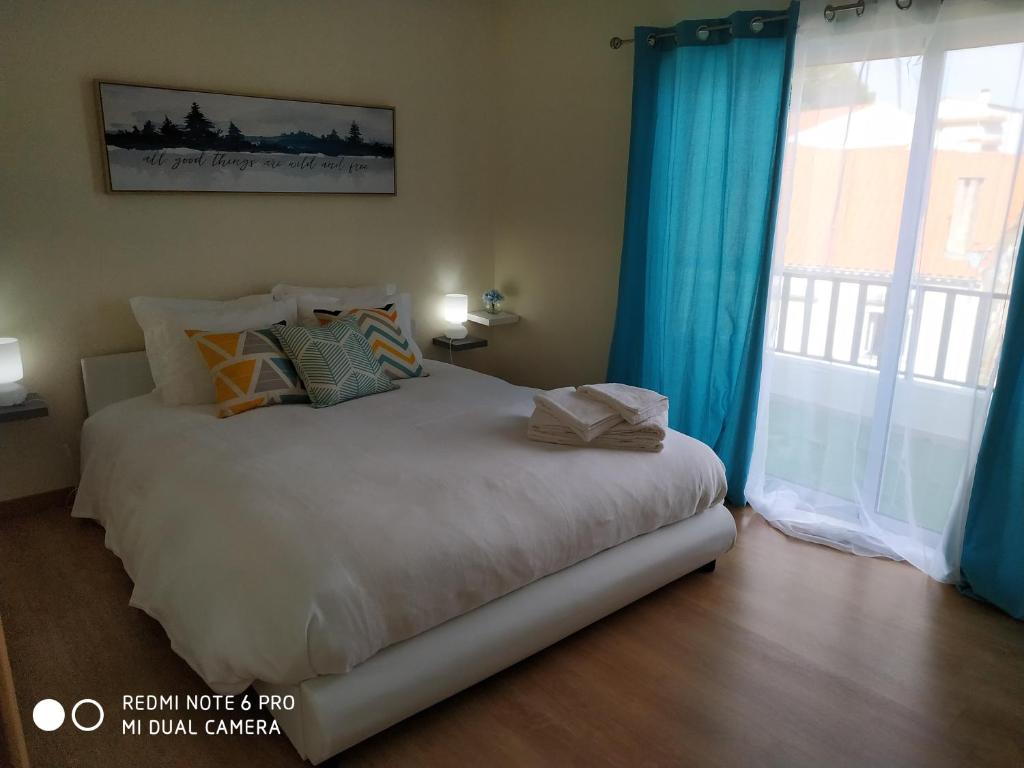 a bedroom with a bed with blue curtains and a window at Varanda do jardim in Belmonte