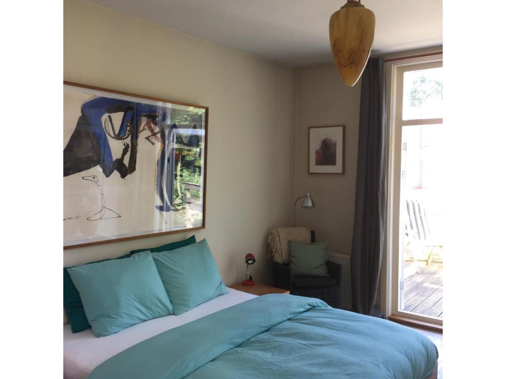 a bedroom with a bed with blue sheets and a window at Bed & Breakfast Leonie in The Hague