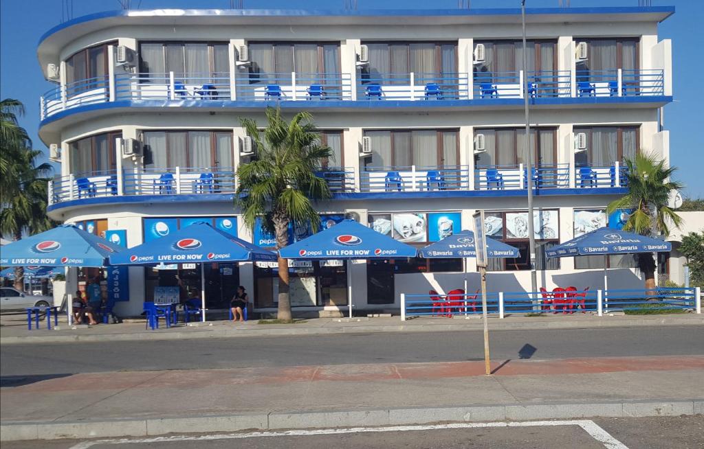 un bâtiment avec des parasols bleus devant lui dans l'établissement Hotel Cruise, à Anaklia