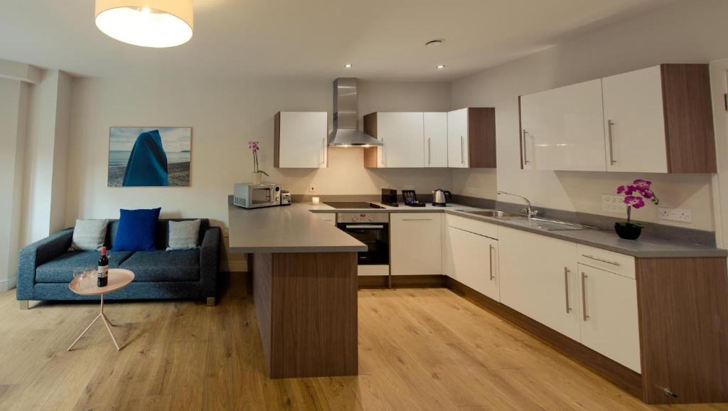 a kitchen with white cabinets and a blue couch at PREMIER SUITES PLUS Glasgow Bath Street in Glasgow