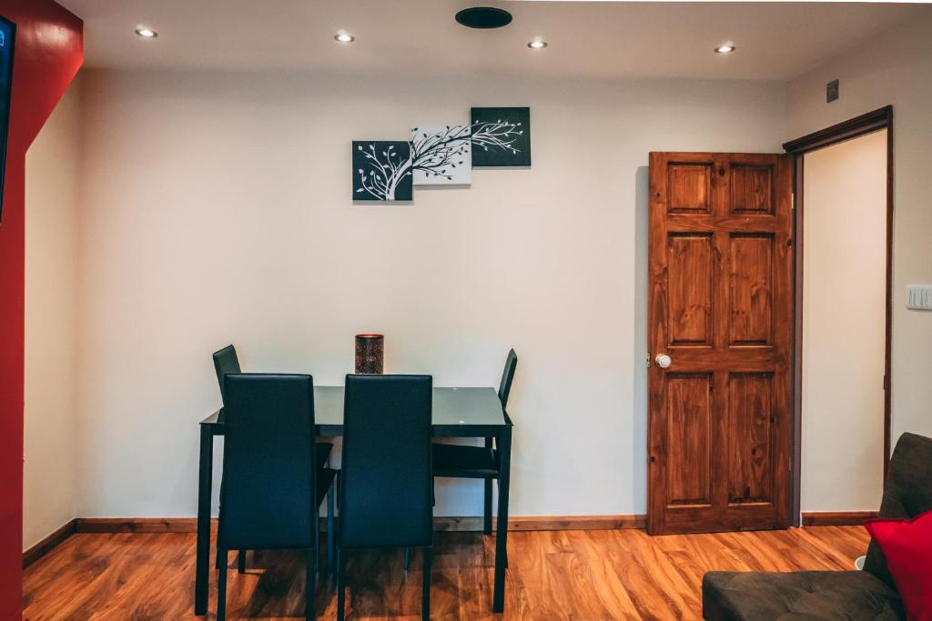 een eetkamer met een tafel en stoelen en een deur bij Hotel Quality Stay,2 bed Apartment near the City Centre, 2min Walk from Metro Station in Londen