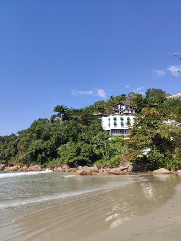 a house on top of a hill next to a beach at Wembley Beach Apto 704 in Ubatuba