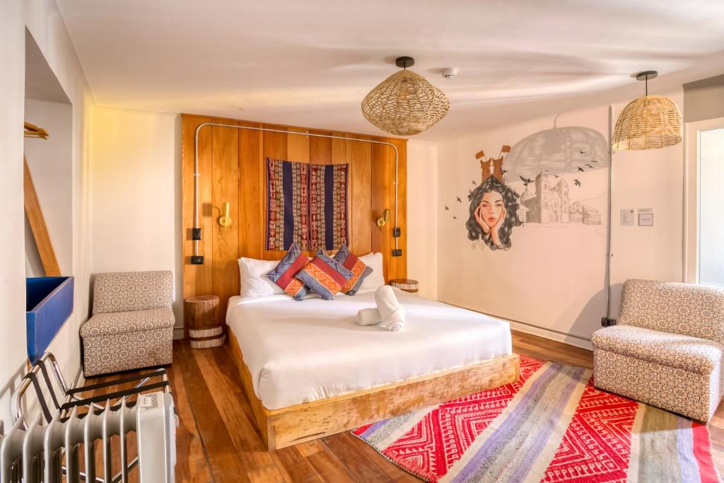 a bedroom with a bed and two chairs at Selina Saphi Cusco in Cusco