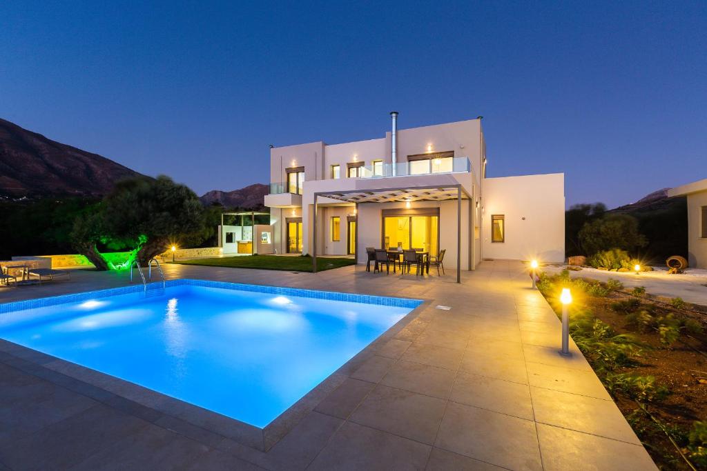 a villa with a swimming pool in front of a house at Villa Anemolia in Lefkogeia