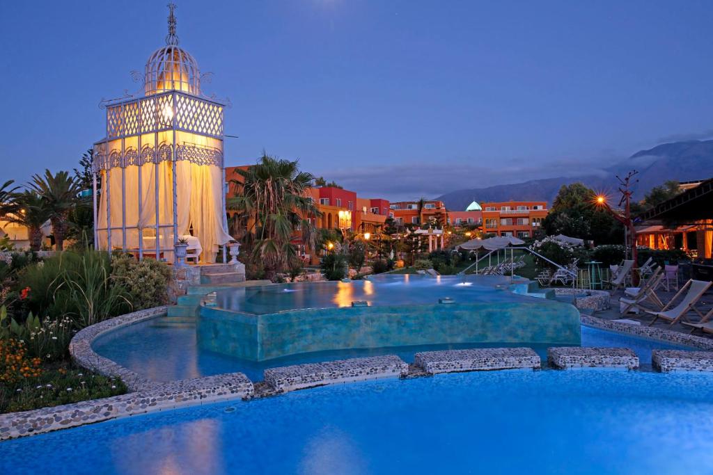 a swimming pool with a clock tower at night at Orpheas Resort Hotel (Adults Only) in Georgioupolis
