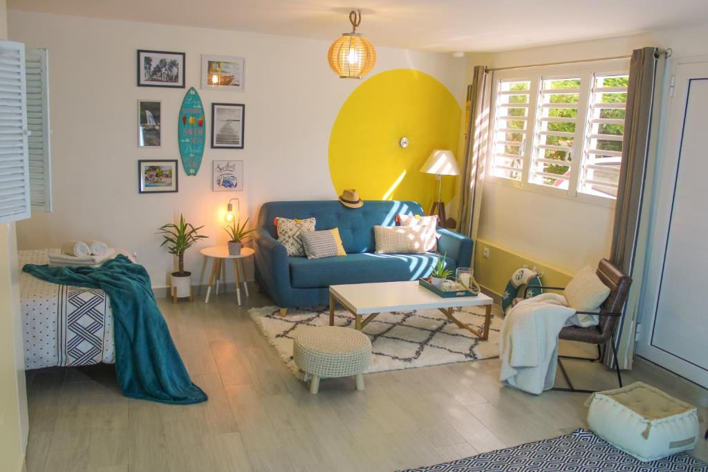 een woonkamer met een blauwe bank en een tafel bij COLIBRIS PARADISE LA MARINA in Le Gosier