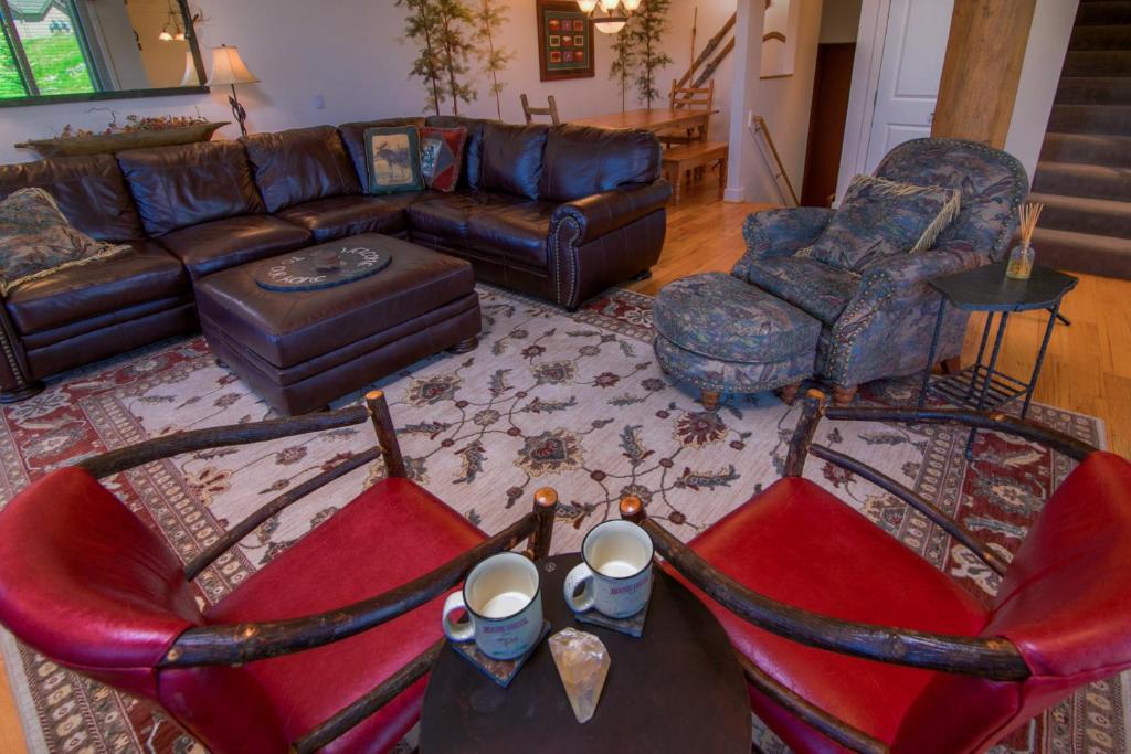 sala de estar con sofá de cuero y sillas en Saddle Ridge Townhome I-5, en Big Sky