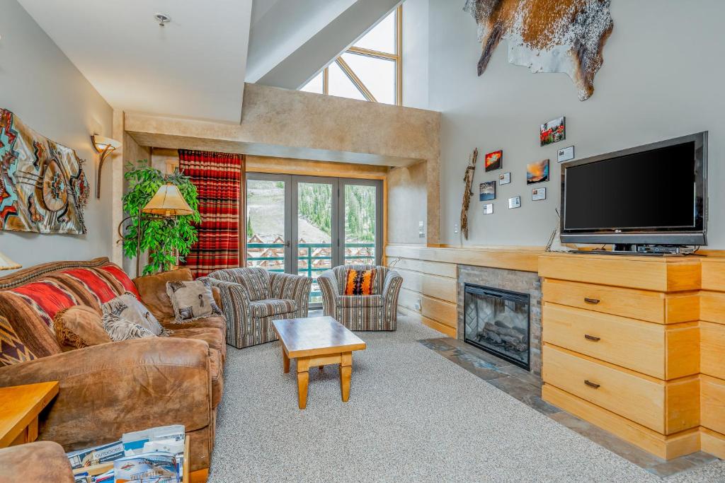 a living room with a tv and a fireplace at Slopeside in Big Sky in Big Sky Mountain Village