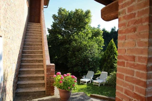 eine Terrasse mit 2 Stühlen, einem Blumentopf und einer Treppe in der Unterkunft “Il Nespolino” Tuscan Country House in Siena