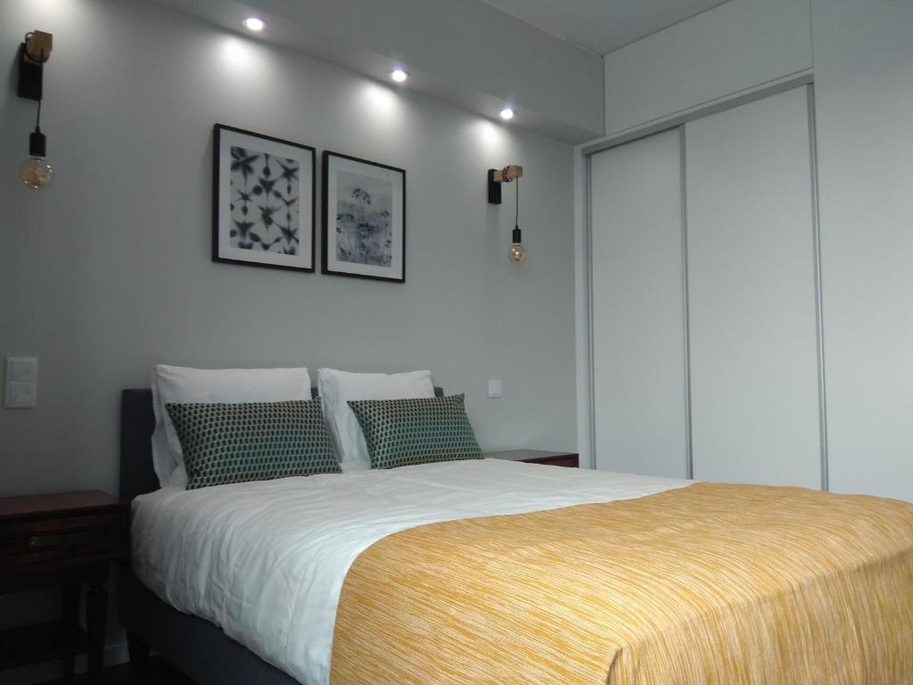 Schlafzimmer mit einem Bett mit weißer Bettwäsche und grünen Kissen in der Unterkunft Chez Moi Bolhão in Porto