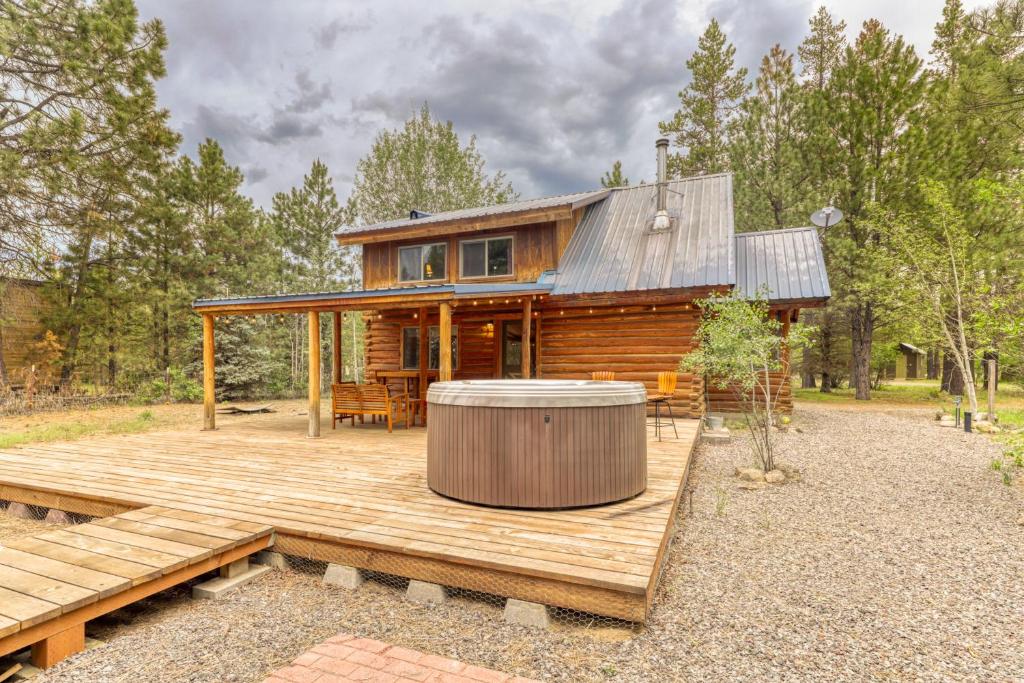 a log cabin with a hot tub on a wooden deck at Whittier Cabin in Three Rivers