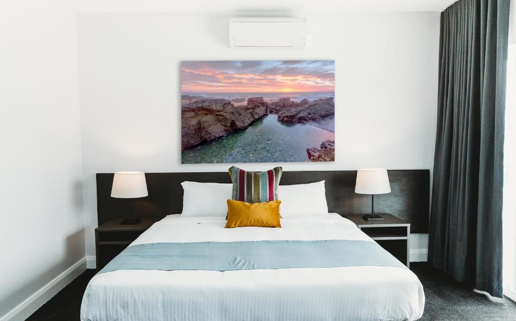 a bedroom with a bed with a painting on the wall at Coniston Hotel Wollongong in Wollongong