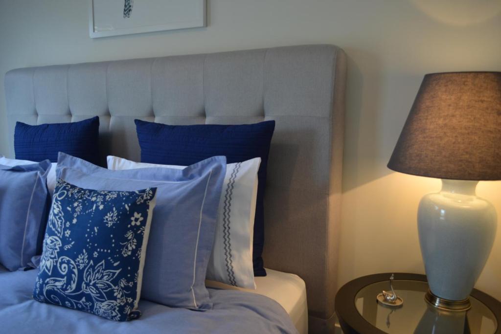 a bed with blue pillows and a lamp on a table at Gone to Barossa in Tanunda