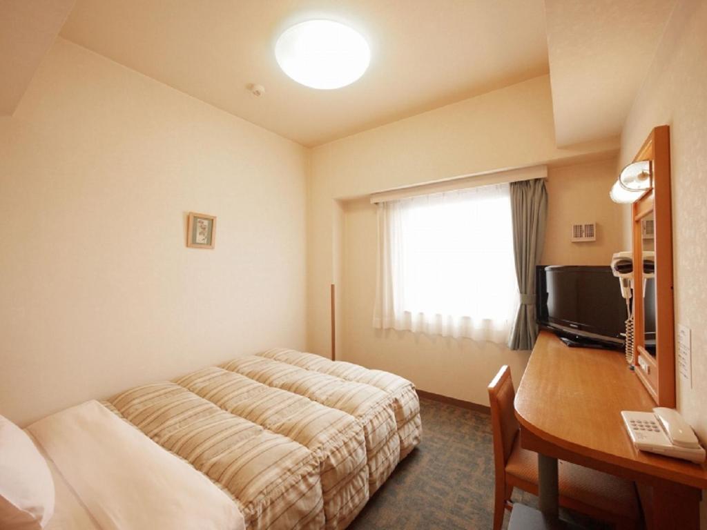 a hotel room with a bed and a desk at Hotel Route-Inn Nagaoka Inter in Nagaoka