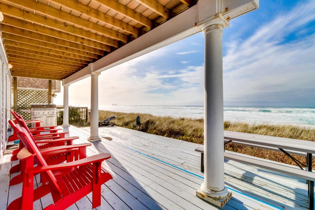 porche con sillas rojas y vistas a la playa en Ace's Beach House, en Rockaway Beach