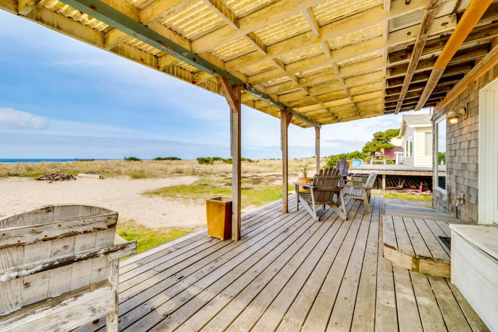 a wooden deck with a table and chairs on the beach at Vinovilla in Rockaway Beach