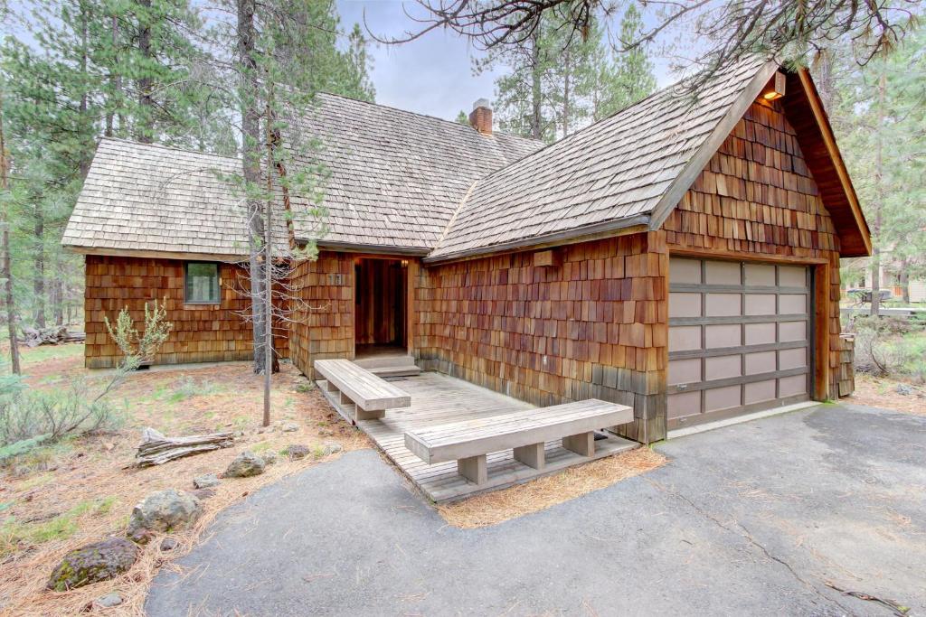 a log cabin with a bench and a garage at Conifer Lane - Lovely Woodland Setting in Sunriver