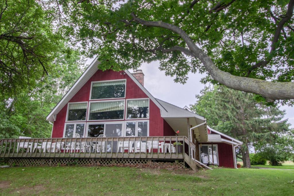 een rood huis met een veranda en een boom bij Southern Point Cottage at Inselheim Road in South Hero