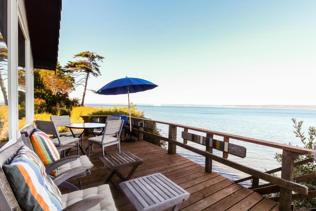 a deck with chairs and a table and an umbrella at The Artists' Beachhouse in Marrowstone