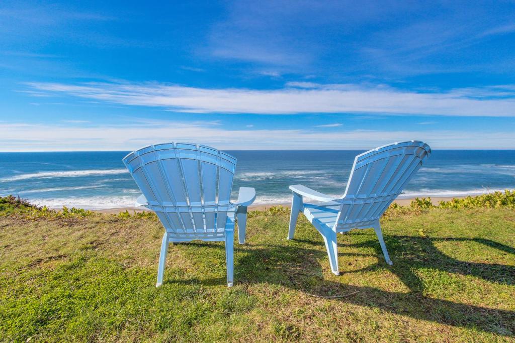 zwei blaue Stühle auf einem Hügel mit Blick auf den Ozean in der Unterkunft Sea Castle BeachFront Getaway in Lincoln Beach