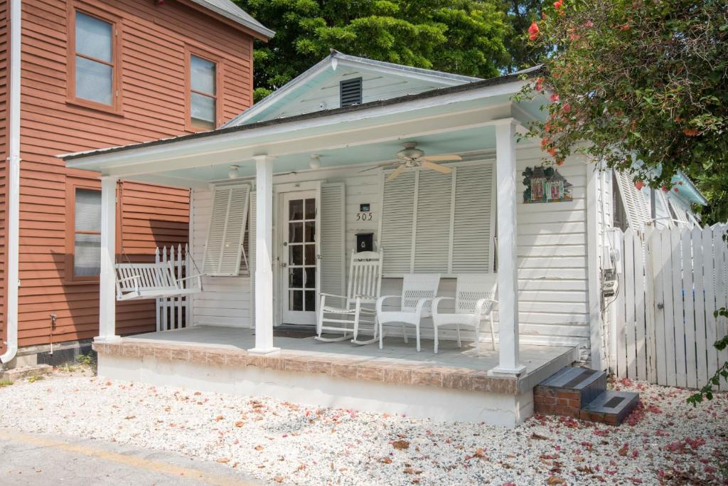 Casa blanca con sillas blancas en el porche en Amelia House en Key West