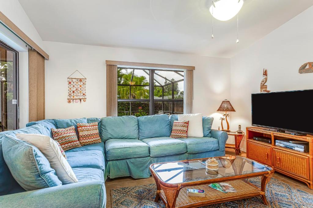 uma sala de estar com um sofá azul e uma televisão em Palm Frond Ranch em Naples