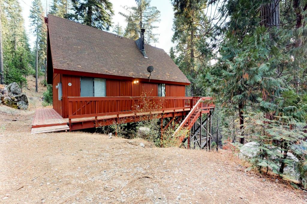 a small red cabin with a bridge in the woods at Deaver's Place in Shaver Lake