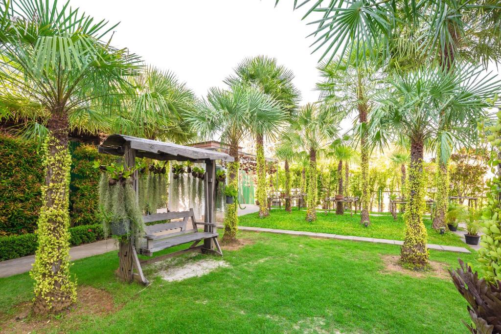 a park with a bench and palm trees at Sungthong Kamala Beach Resort in Kamala Beach
