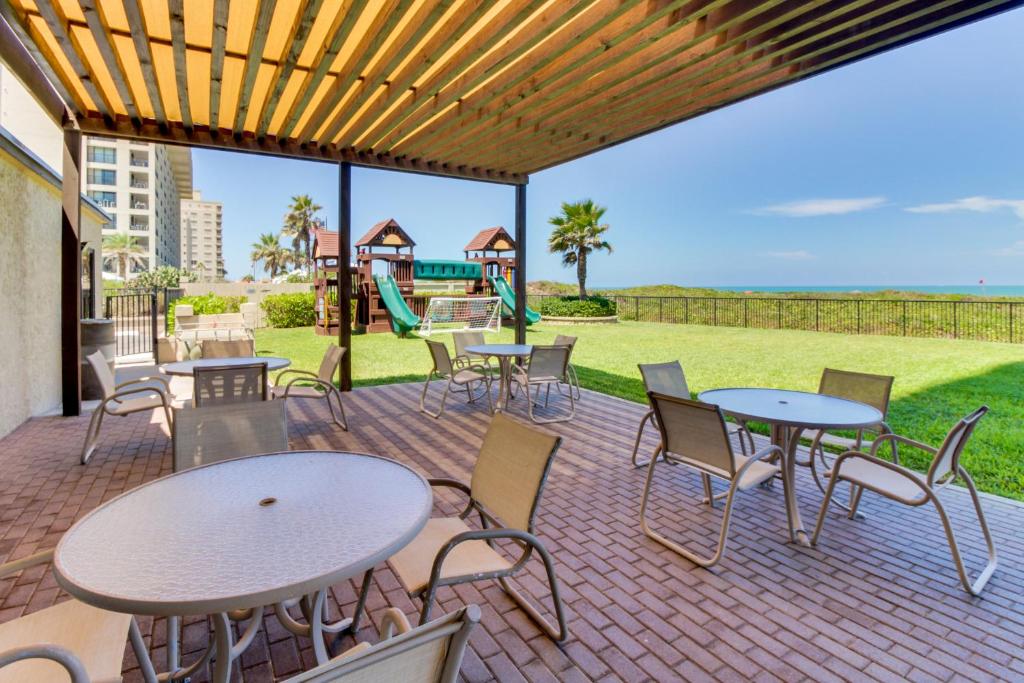 a patio with tables and chairs and a playground at Ocean Vista #1101 in South Padre Island