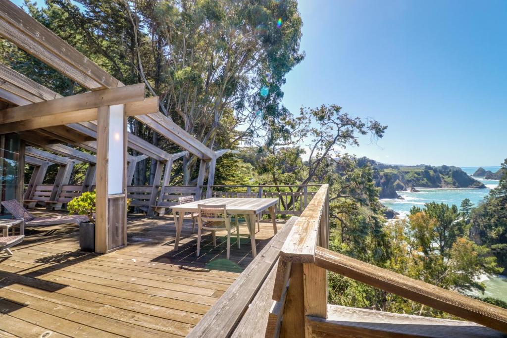 una terraza de madera con mesa, sillas y el océano en Elk Mid-Century - Guest House en Elk